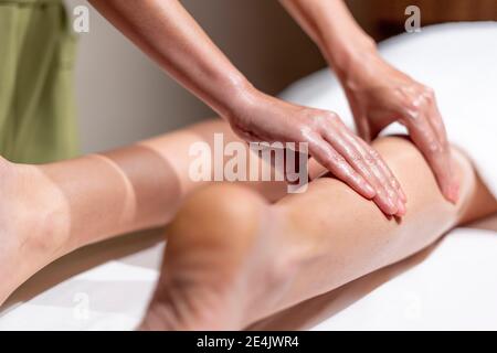 Donna matura terapeuta massaggiando la gamba della donna a tavola in salute centro benessere Foto Stock