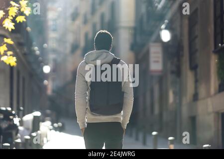 Uomo che trasporta lo zaino mentre si è in piedi con le mani in tasca città Foto Stock