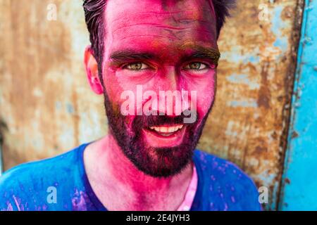 Primo piano di un uomo sorridente con il volto rosa durante Holi festival Foto Stock
