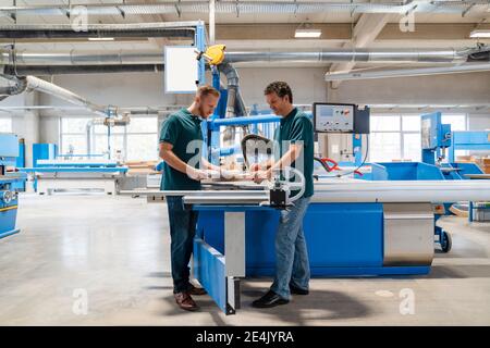 Due falegnami maschi che lavorano insieme nella sala di produzione Foto Stock