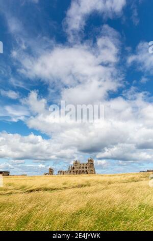 Vista in lontananza dell'abbazia di Whitby contro il cielo nuvoloso durante il giorno di sole, Yorkshire, Regno Unito Foto Stock