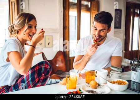 Felice giovane coppia seduto al tavolo e facendo colazione a. casa Foto Stock