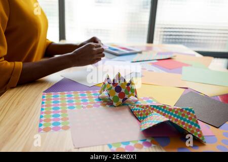 Artista Origami seduto in studio pieghevole carta colorata Foto Stock