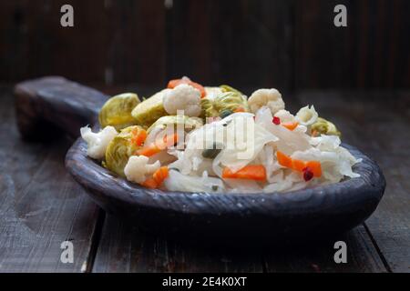 Verdure fatte in casa e sauerkraut decapaggio in rustico piatto di legno. Cibo probiotico sano pieno di vitamine. Foto Stock
