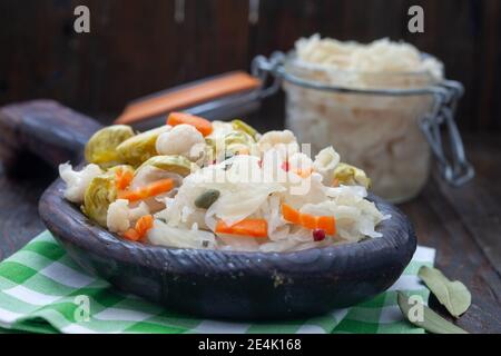 Verdure fatte in casa e sauerkraut decapaggio in rustico piatto di legno. Cibo probiotico sano pieno di vitamine. Foto Stock