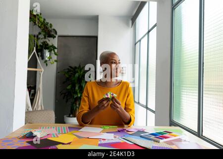 Artista Origami seduto in studio che lavora con carta colorata Foto Stock