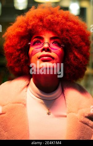 Primo piano di donna elegante con capelli afro che indossa occhiali da sole mentre guardando in alto Foto Stock