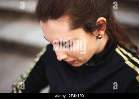 Ritratto di giovane donna in abbigliamento sportivo bianco dietro le scale di legno nel parco. Foto Stock