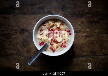 Porridge con mele, cannella e semi di melograno in ciotola sul tavolo Foto Stock