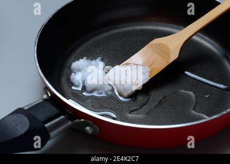 Olio di cocco con spatola di bambù in padella Foto Stock