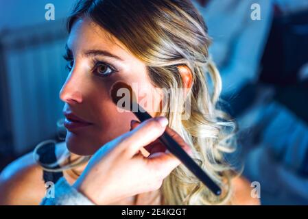 Mano che applica il make up sul viso della giovane donna Foto Stock