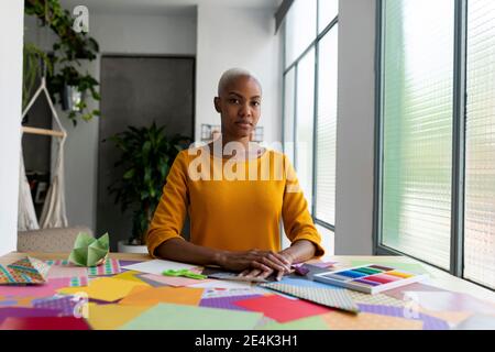 Artista Origami seduto in studio con carte colorate Foto Stock