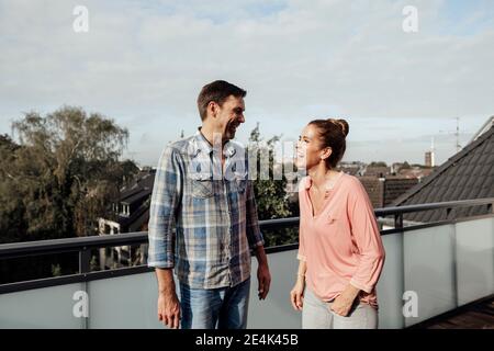 Una coppia giovane e allegra che ride mentre si alza in piedi sul balcone Foto Stock