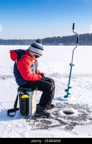 Boy ama la pesca invernale sul ghiaccio del lago 13 Foto Stock