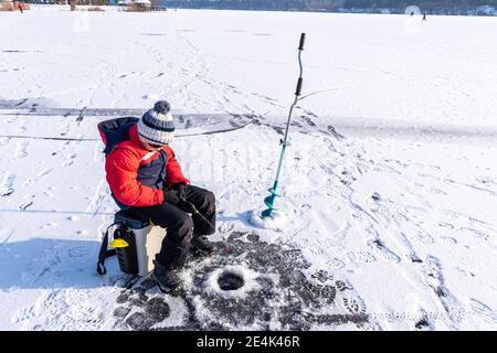 Boy ama la pesca invernale sul ghiaccio del lago 14 Foto Stock