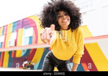 Donna sorridente che punta il dito mentre si trova all'aperto Foto Stock