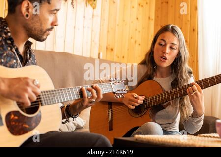 Donna che canta mentre suona la chitarra con l'uomo a casa Foto Stock
