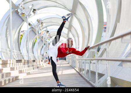 Sorridente sportivo che si allenano mentre si fanno le fessure sul passaggio Foto Stock