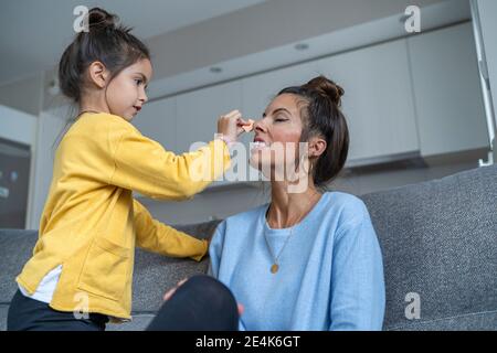 Figlia che applica il make-up alla madre a casa Foto Stock