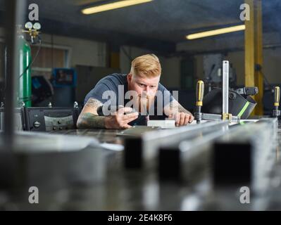 Tecnico del metallo che controlla il materiale della giunzione mentre lavora in fabbrica Foto Stock