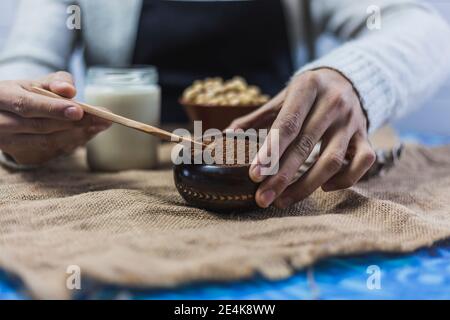 Mani di uomo che prendono il cucchiaio di cacao in polvere Foto Stock