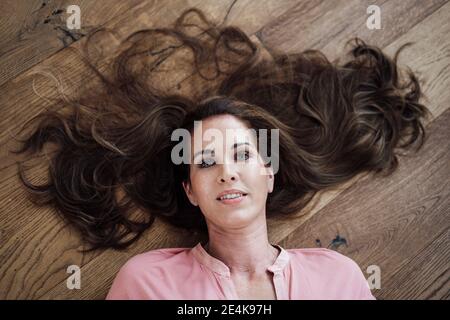 Bella donna matura sdraiata sul pavimento a casa Foto Stock