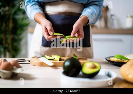 Sezione centrale di avocado peeling donna Foto Stock