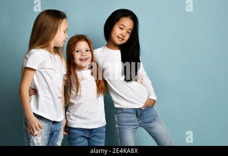 Misto gara internazionale felice ragazze amici in jeans e bianco t-shirt in piedi e abbracciare insieme sorridendo ridendo Foto Stock