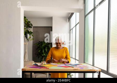 Artista Origami seduto in studio che lavora con carta colorata Foto Stock