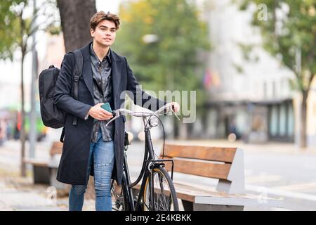 Bel giovane uomo che ruota in bicicletta in città Foto Stock