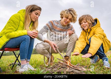 Tre fratelli che iniziano il falò in campo erboso Foto Stock