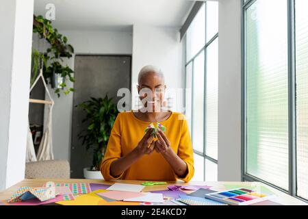 Artista Origami seduto in studio che lavora con carta colorata Foto Stock