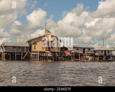 Belen, Perù - maggio 2016: Chiesa e altre case su palafitte nella pianura alluvionale del fiume Itaya, la parte più povera di Iquitos - Belén. Venezia del latino A. Foto Stock