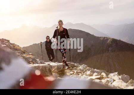 Sportivo e donna con palo da trekking e zaino a piedi sul sentiero di montagna Bschiesser a Tirolo, Austria Foto Stock