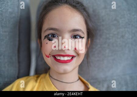 Ragazza sorridente con il make-up seduto a casa Foto Stock