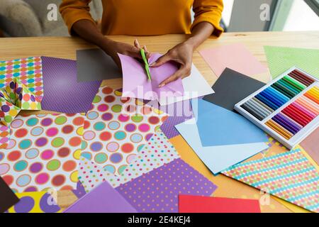 Artista Origami seduto in studio pieghevole carta colorata Foto Stock