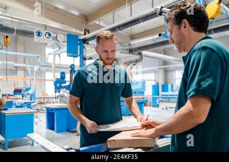 Due falegnami maschi che lavorano insieme nella sala di produzione Foto Stock