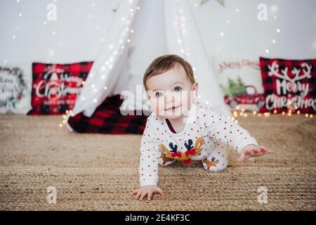 Cute baby girl sorridente mentre strisciando a casa durante Natale Foto Stock