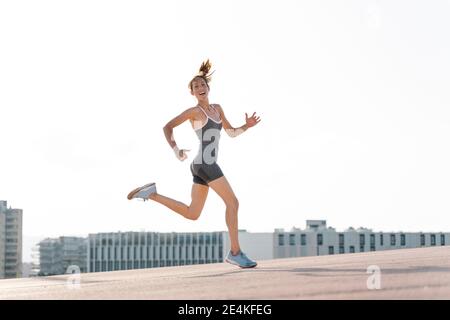 Felice sportivo che corre contro il cielo limpido in gthe city Foto Stock