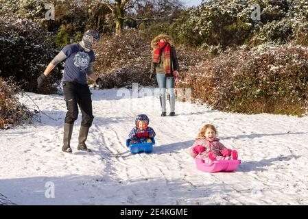 Slittino in famiglia sulla neve. Divertirsi a scivolare in discesa su slitte, slittini. Foto Stock