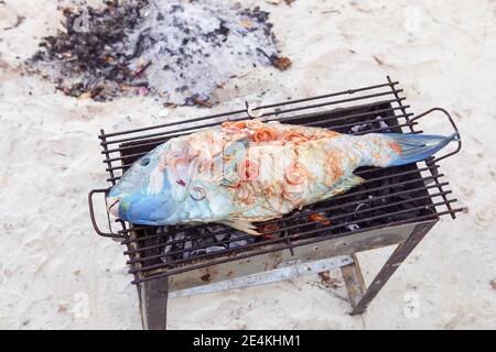 Barbecue, pesce corallo alla griglia. Grigliare sulla spiaggia, pesce tropicale appena pescato con verdure fresche. Zanzibar cibo locale. Foto Stock