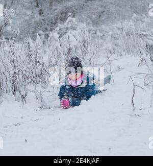 Kidderminster, Regno Unito. 24 gennaio 2021. Tempo nel Regno Unito: La caduta di neve di prima mattina sorprende i residenti nelle Midlands con la neve pesante che causa una coperta bianca invernale tra le 8:00 e le 10:00. Amber è fuori slitta con suo fratello, Jackson, con la mamma in fondo alla collina in attesa di catturarli e papà pazientemente in attesa di avere il suo turno in cima! Credit: Lee Hudson/Alamy Live News Foto Stock