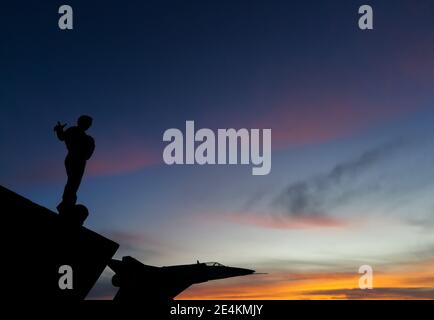 RIO GALLEGOS, ARGENTINA - 09 luglio 2020: RIO GALLEGOS, ARGENTINA - 8 LUGLIO 2020: Tramonto e sagome dei monumenti, l'uomo chiamato monumento alla caduta Foto Stock