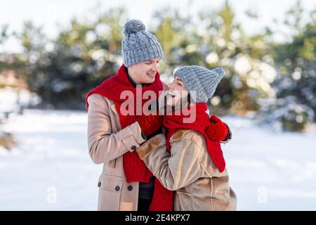 Giovane coppia emozionale che si diverte passeggiando nella foresta invernale Foto Stock