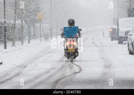 Londra, Regno Unito. 24 gennaio 2021. Un pilota ciclomotore guida con cautela attraverso la neve a Brentford. Credit: Liam Asman/Alamy Live News Foto Stock