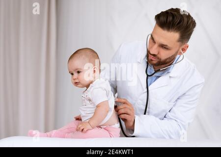 Medico che esamina il bambino che ascolta i polmoni con stetoscopio in clinica Foto Stock