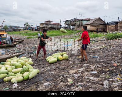 Iquitos, Perù - Set 2019: Gli uomini stanno spostando i frutti da una barca. Sullo sfondo, sulle rive del fiume Itaya, si nota un inquinamento enorme. Basso A. Foto Stock