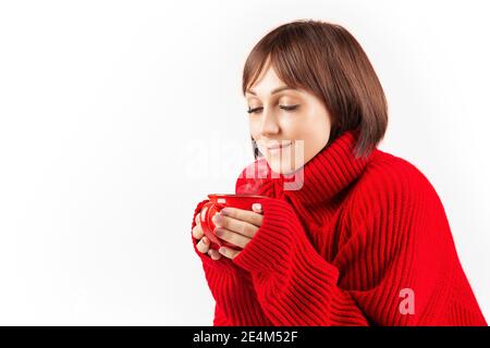 una ragazza con un bob corto in un maglione rosso si siede con una tazza di tè o caffè, isolare Foto Stock