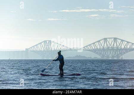 Saint Davids Bay, Dalgety Bay, Fife, Scozia. 24 gennaio 2021. Un paddle boarder godendo del sole invernale sul Firth of Forth vicino al Forth Bridge, al Saint Davids Bay Fife. © Richard Newton / Alamy Live News Foto Stock