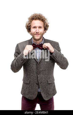 Ritratto di riuscito uomo d'affari con capelli ricci tenendo arco-cravatta e sorridendo a. fotocamera Foto Stock